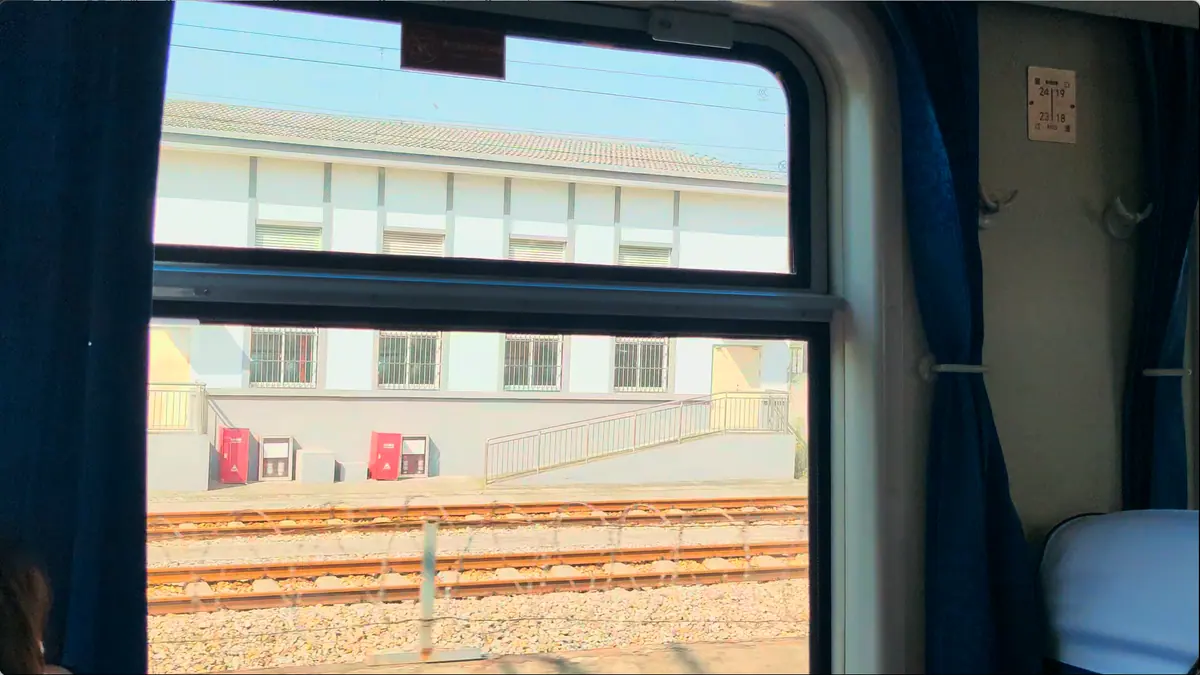 A view from a train window with railway tracks and a building outside.