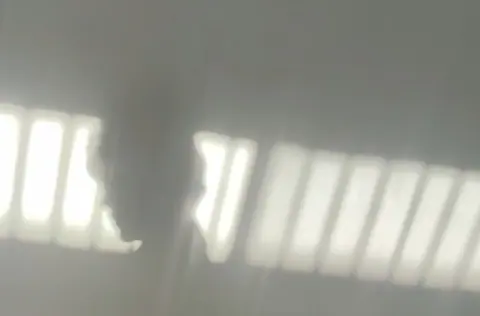 A blurry shadow of a person cast near bright window light.
